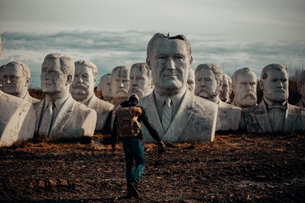 person in black hoodie walking on dirt in front of bust